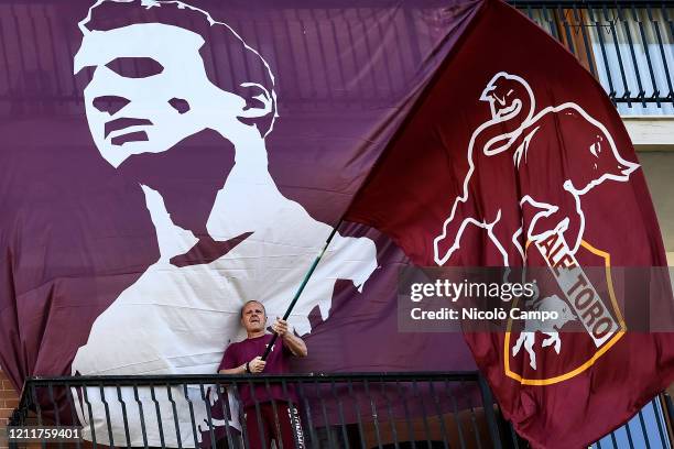 Fan of Torino FC waves a flag from his balcony to commemorate the Superga tragedy while there is a banner depicting the captain of Grande Torino...