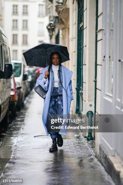 Guest wears a blue wool coat, a white turtleneck pullover, a blue denim jacket, blue pants, black leather shoes, a bag, during Paris Fashion Week -...