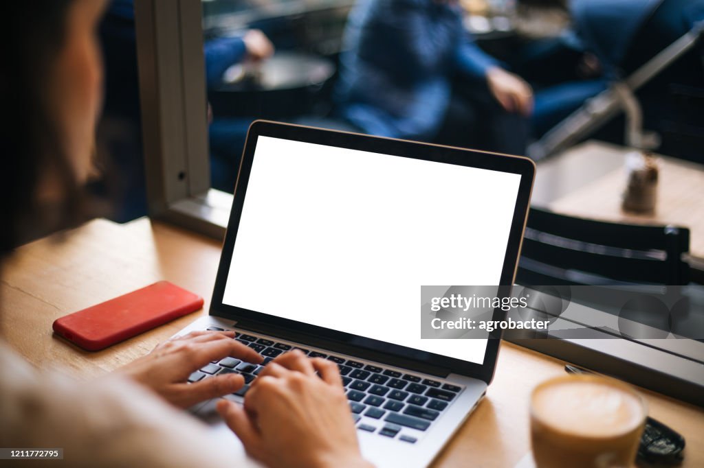 Hand using laptop with blank white screen at cafe