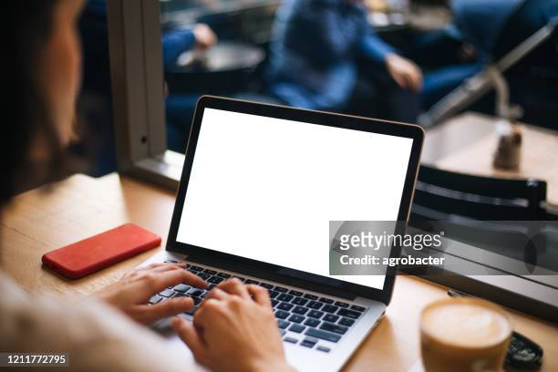 hand using laptop with blank white screen at cafe - laptop imagens e fotografias de stock