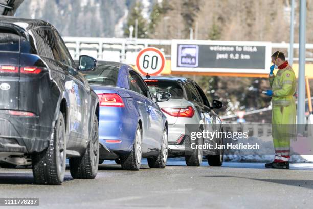 Man in protective gear is seen with an clinical thermometer to check the temperature of the passengers in cars arriving from Italy at the Brenner...