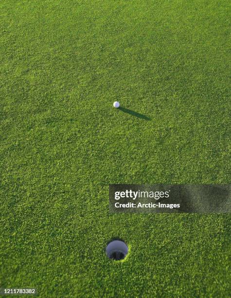 golf ball close to the hole - grass court stock-fotos und bilder