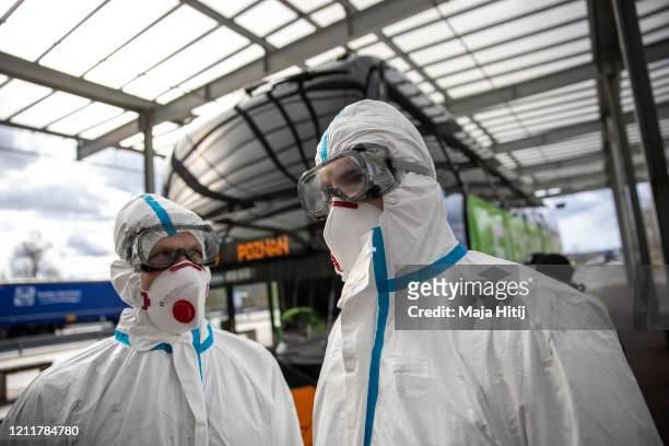 Health workers wear a protective mask and suit as they stands next to a bus to screen passengers temperature at the German-Polish border on March 11,...