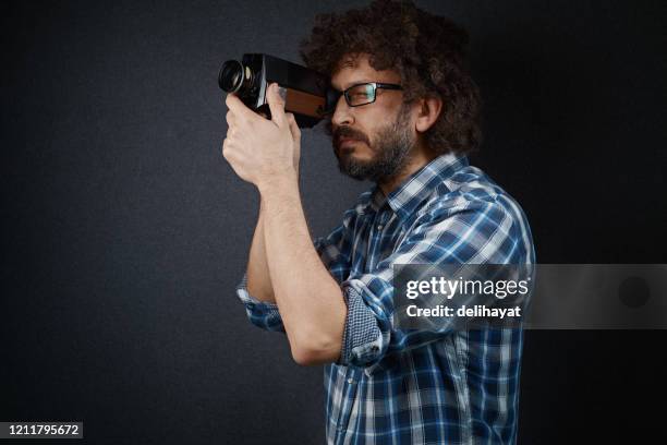 young cinematographer shooting with an old fashioned film camera - cameraman grey background stock pictures, royalty-free photos & images