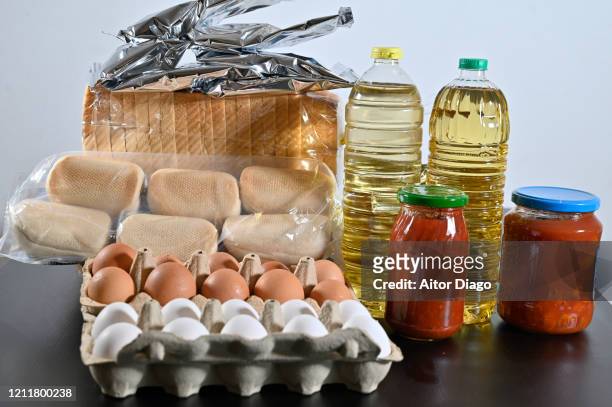 basic food on a table storable for a long time. eggs, oil, bread, tomato cans and bags of potato puere - dispensa foto e immagini stock