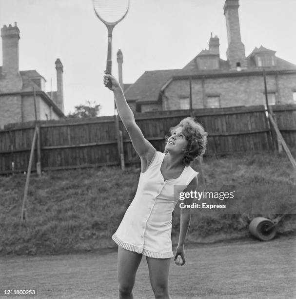 Australian tennis player Evonne Goolagong wearing a white tennis dress, her racquet raised as if serving, 8th June 1972.