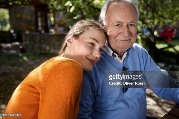 portrait of smiling senior man and young woman in garden - daughter stock-fotos und bilder
