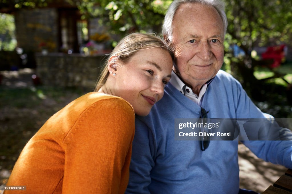 Portrait of smiling senior man and young woman in garden