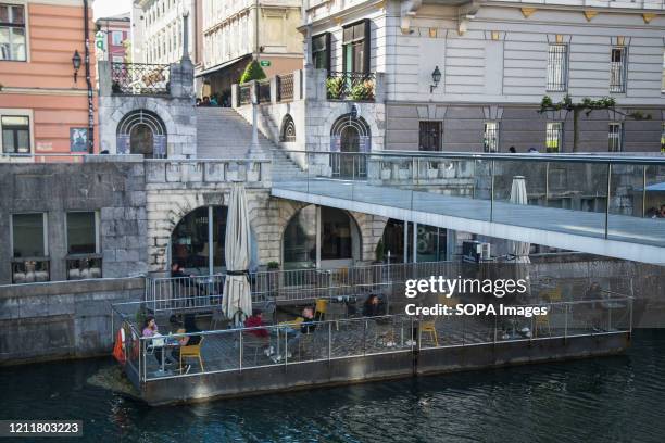People are seen drinking on the outdoor floating terrace at Ljubljanica river during the lockdown. Outdoor terrace bars, restaurants along with...
