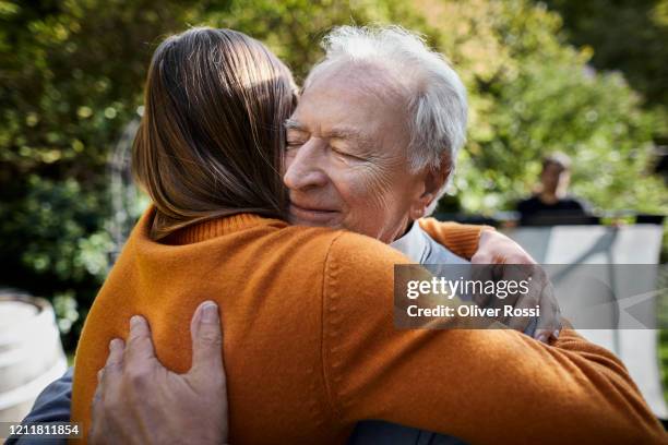 senior man and young woman hugging in garden - daughter dad stock pictures, royalty-free photos & images