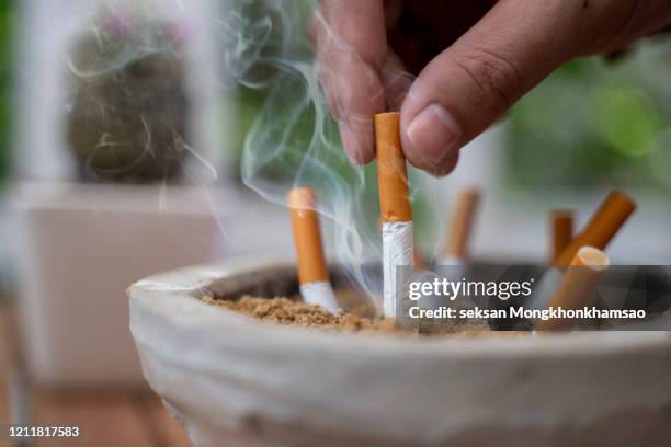 close up on man man extinguishes the cigarette in the ash tray quitting no smoking lung health problems - cigarette photos et images de collection