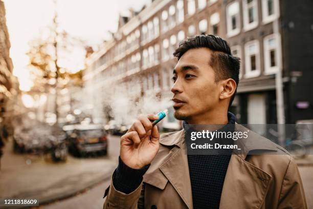 japanese man vaping in the street - vape stock pictures, royalty-free photos & images