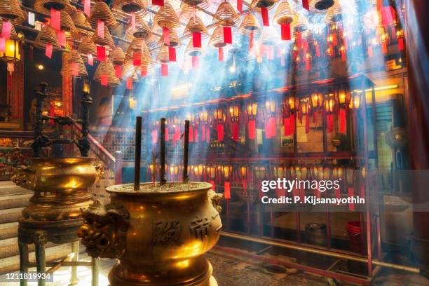 templo man mo na ilha de hong kong com raios solares e incenso - templo de man mo - fotografias e filmes do acervo