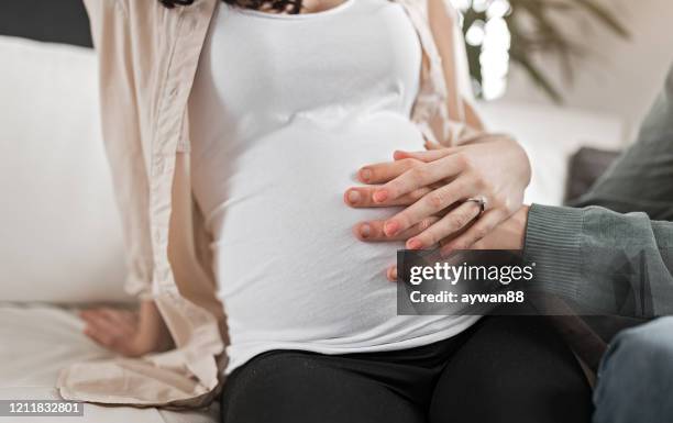 mari touchant l’estomac de la femme enceinte - donner un coup de pied photos et images de collection