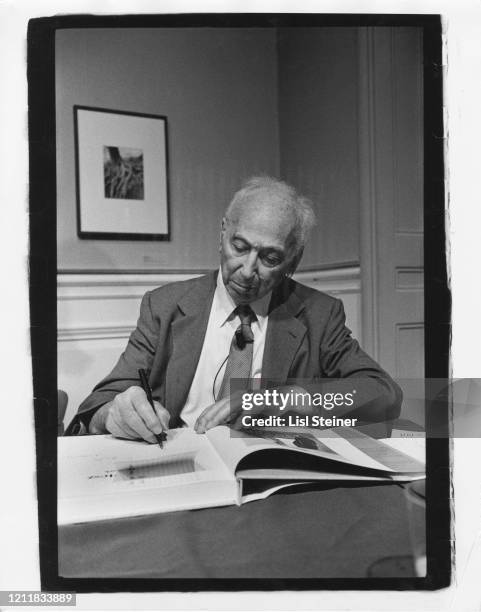 Hungarian-born American photographer Andre Kertesz autographs a book, 1960.