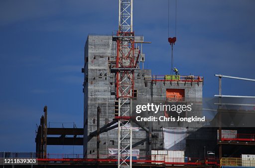 Construction Worker Unloading Crane on Skyscraper Construction Construction Worker Unloading Crane on Skyscraper Construction