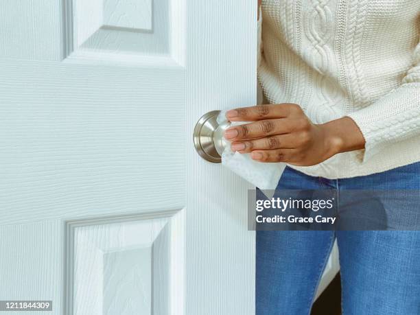 woman cleans interior doorknob using disinfectant wipe - doorknob foto e immagini stock