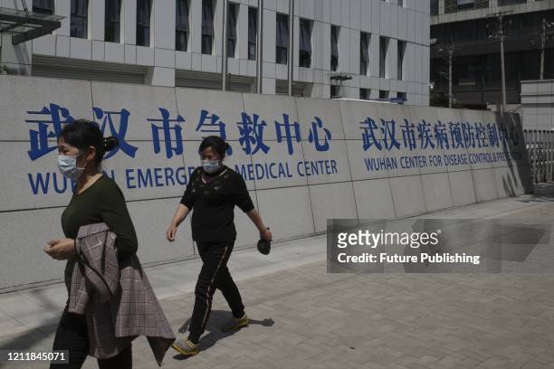 People pass by the compound of Wuhan Center for Disease Control and Prevention in Wuhan in central China's Hubei province Saturday, April 25, 2020.-...