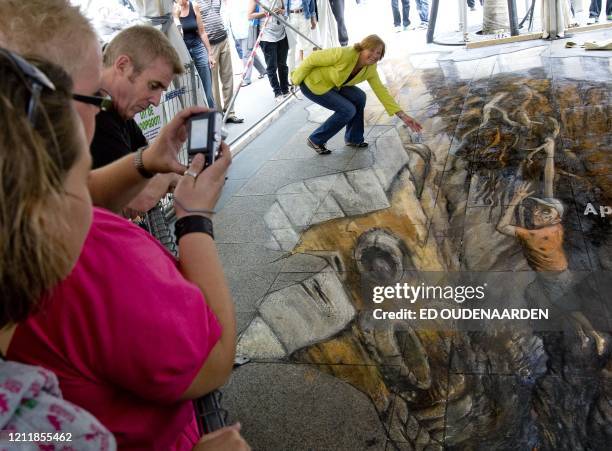 British artist Julian Beever poses by her painting on a sidewalk in Rotterdam, Netherlands, on August 9, 2008. The painting, which was made with...