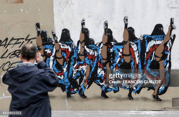 Un homme photographie, le 21 mars 2010, un mur dans le 10e arrondissement de Paris, sur lequel est peinte une fresque sauvage de l'artiste de rue...