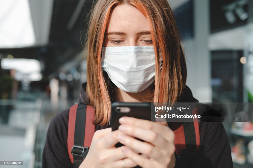 在公共場所使用手機戴防護面罩的婦女。