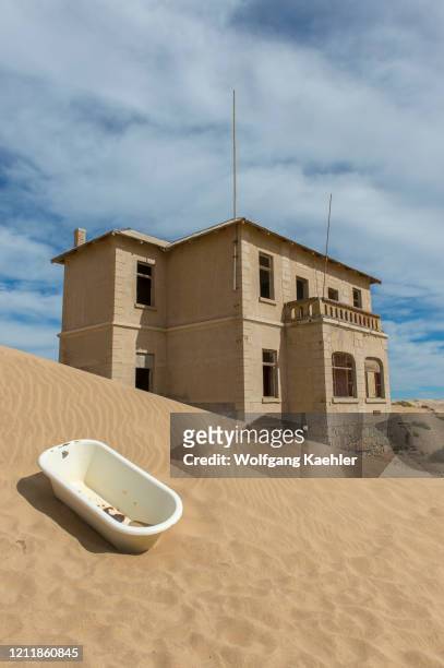 Bathtub in the sand in front of a building in the abandoned German diamond mining settlement of Kolmanskop near Luderitz, Namibia.