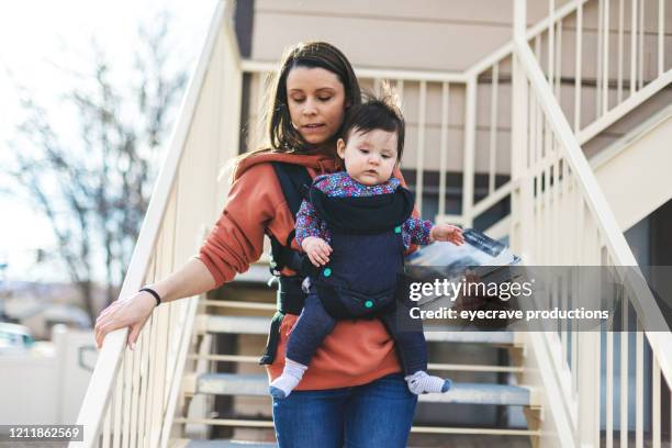 millennial mother college student near housing with infant in urban environment - family serious stock pictures, royalty-free photos & images