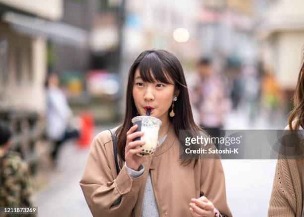 young woman drinking tapioca tea on street - tapioca stock pictures, royalty-free photos & images