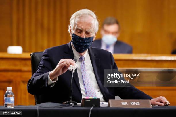 Sen. Angus King, I-Maine, wipes his microphone as he arrives for a Senate Intelligence Committee nomination hearing for Rep. John Ratcliffe, R-Texas,...