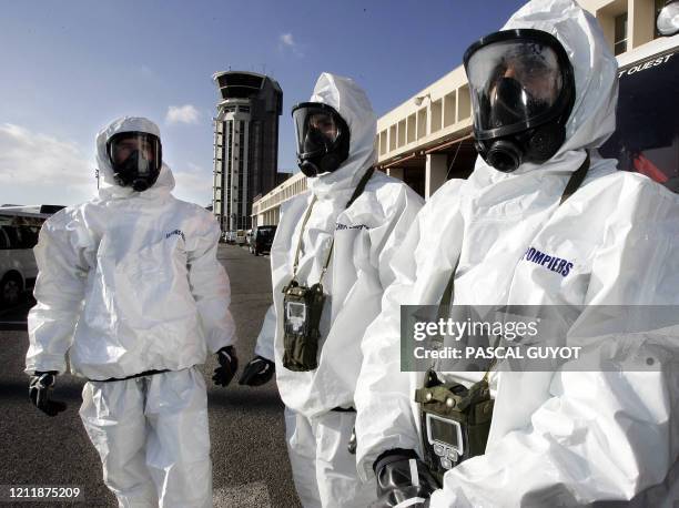 Des sapeurs-pompiers s'équipent de tenues NBC lors d'un exercice nucléaire, radiologique, bactériologique et chimique le 09 janvier 2005 à l'aéroport...