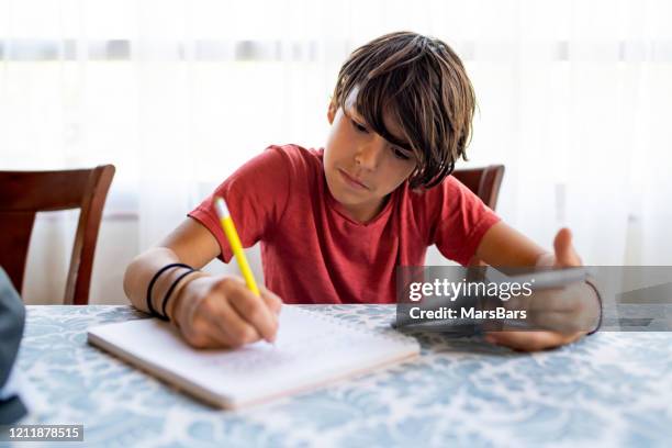 latinx preadolescent boy doing homework with a digital tablet - 13 year old stock pictures, royalty-free photos & images