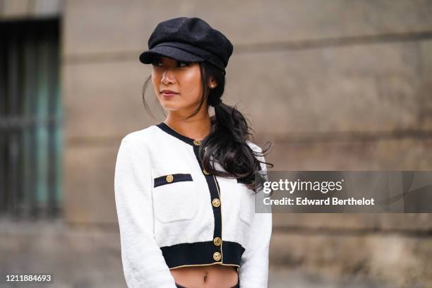 Guest wears a black cap, earrings, a black trimmed white Chanel crop top, outside Giambattista Valli, during Paris Fashion Week - Womenswear...