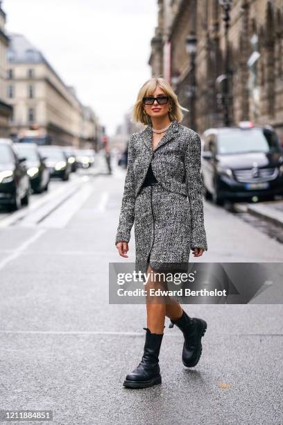 Xenia Adonts wears sunglasses, earrings, pearl necklaces, a heather grey Spencer jacket, a heather grey skirt with a black leather trim, black...