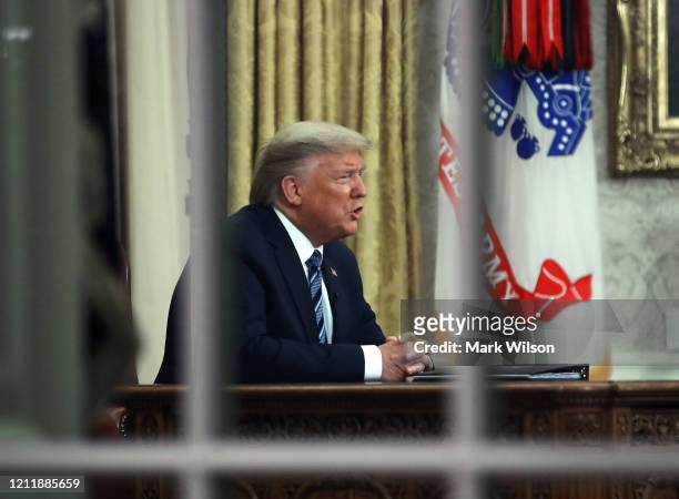 President Donald Trump is seen through a window in the Oval Office as he addresses the nation on the response to the COVID-19 coronavirus, on March...