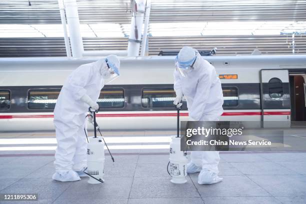 Disinfection workers wearing protective suits pump up disinfection buckets at a railway station on March 3, 2020 in Beijing, China.