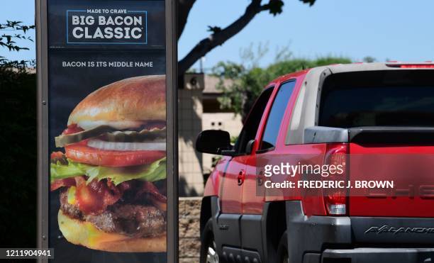 Driver in a vehicle places his order from a drive-thru lane at a Wendy's fast food resturant in Alhambra, California on May 5, 2020. - A sign...