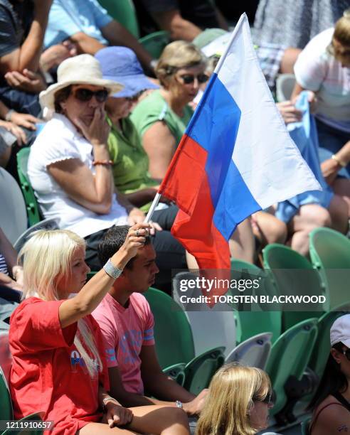 Spectator waves a flag as she cheers for Russian tennis player Nadia Petrova serves during her women's singles quarter-final match against Belgian...