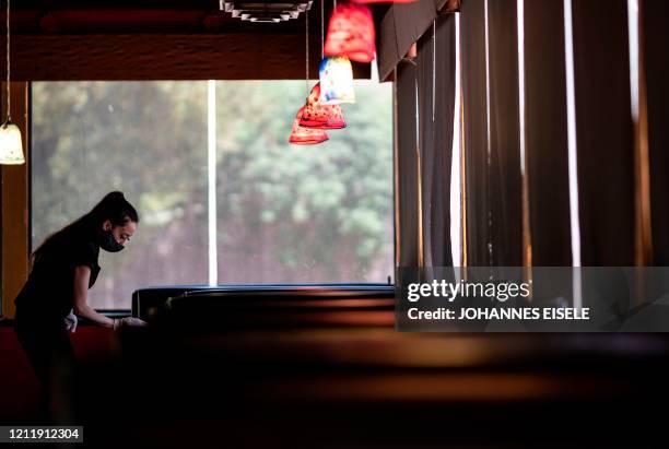 Waitress wearing a mask and gloves disinfects a table in a Restaurant on May 5, 2020 in Stillwater, Oklahoma. - In the face of intimidation against...