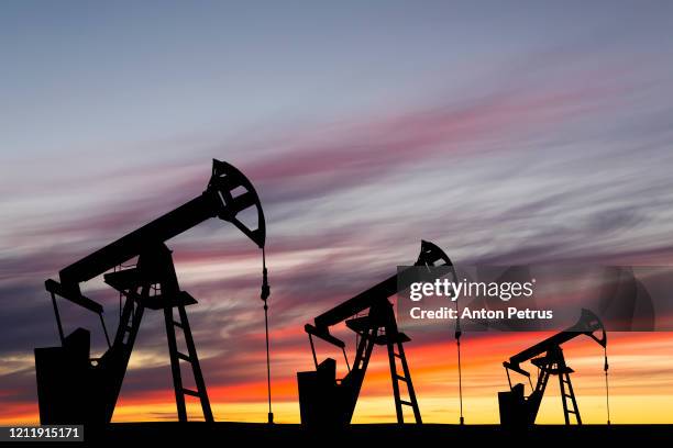 oil pump on a sunset background. world oil industry - piattaforma petrolifera foto e immagini stock