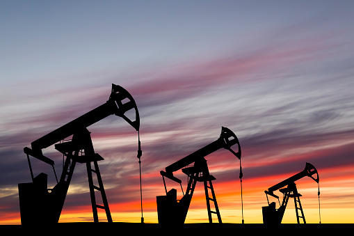 Oil pump on a sunset background. Global oil industry