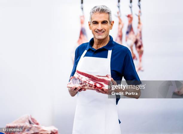 confident butcher holding fresh raw meat - butcher portrait imagens e fotografias de stock