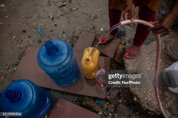 Nepalese woman fills drinking water on a jar near Jadibuti after waiting hours during the 44th day of the lockdown imposed by the government as a...