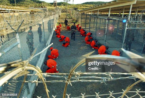 In this photo released 18 January 2002 by the Department of Defense, Al-Qaeda and Taliban detainees in orange jumpsuits sit in a holding area under...