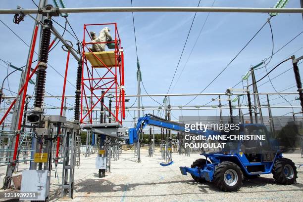 Deux monteurs du Réseau de Transport d'Electricité , protégés par une combinaison et isolés du sol, réparent sous haute tension, le 27 juin 2002, un...