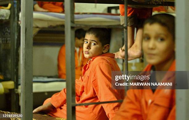 Iraqi boys sit in on their beds in a cell at the Al-Karkh Juvenile Correctional Center in Baghdad, 09 October 2004. Two Hundred boys, all in orange...