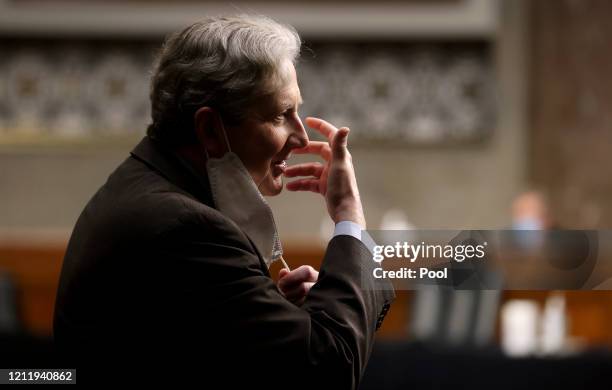Sen. John Kennedy pulls back his protective face mask to talk to another attendee during a Senate Judiciary Committee confirmation hearing on the...