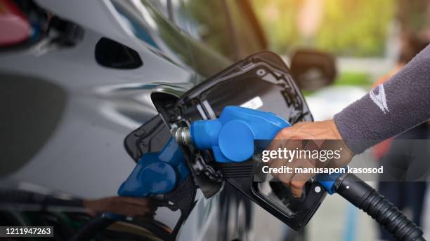 pumping gas at gas pump. closeup of man pumping gasoline fuel in car at gas station. - premium gasoline stock pictures, royalty-free photos & images