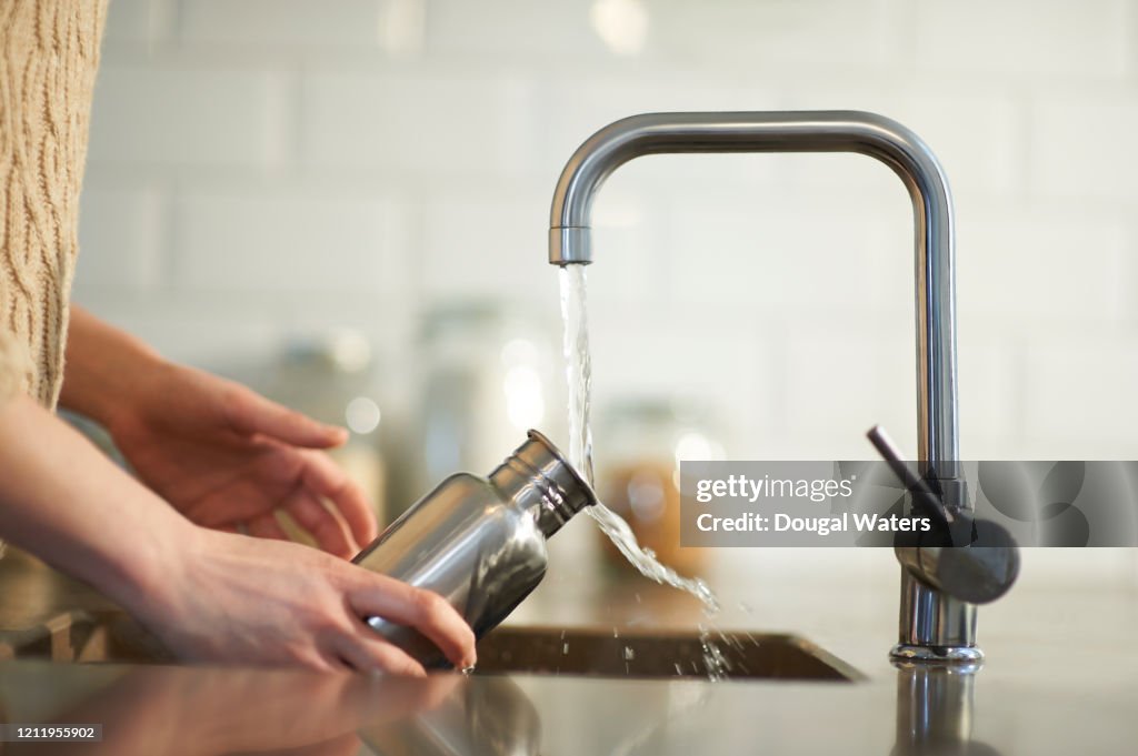 Cleaning a plastic free reusable water bottle in kitchen sink.