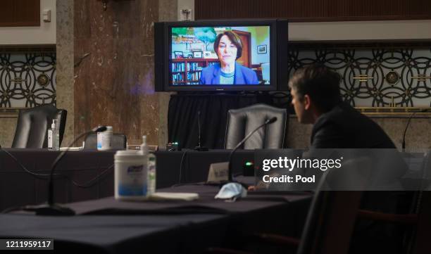 Sen. Amy Klobuchar questions Judge Justin Walker remotely by video link as he sits in a sparsely attended hearing room as part of COVID-19 social...