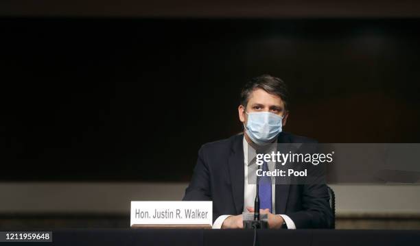 Judge Justin Walker wears a protective face mask as he sits in a sparsely attended hearing room due to social distancing measures because of the...